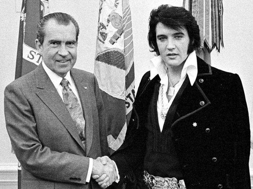 Elvis Presley estrechando la mano a un hombre trajeado